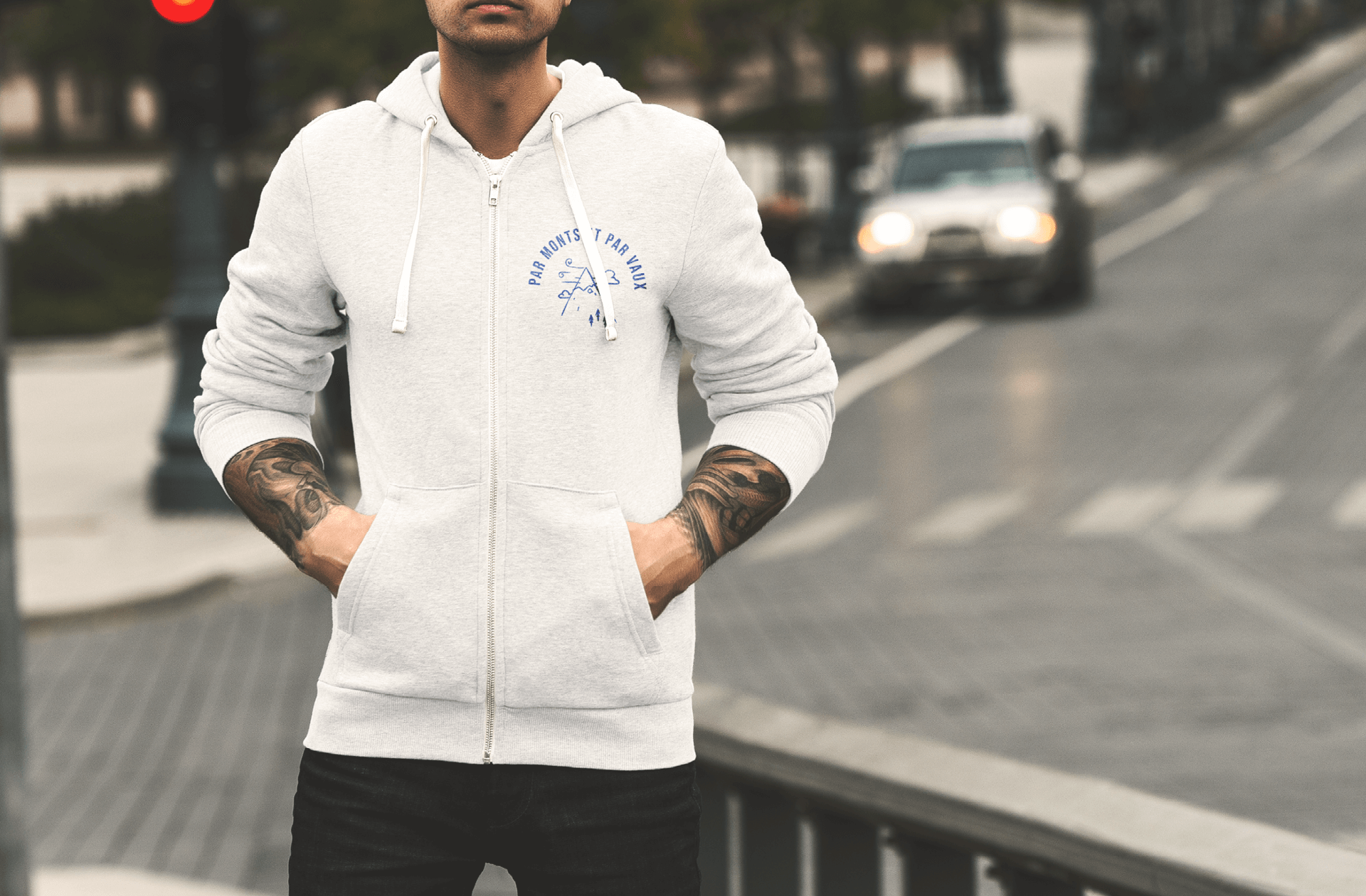 Sweat blanc sur un homme tatoué. Il arbore sur le coeur le visuel de la montagne.